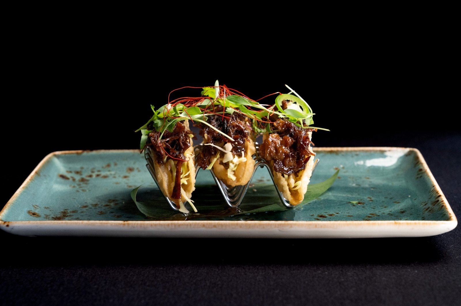 Taco Belle: Pulled teriyaki short ribs paired with serrano rings, spicy citrus slaw, and micro cilantro, all nestled in a soft taco shell.